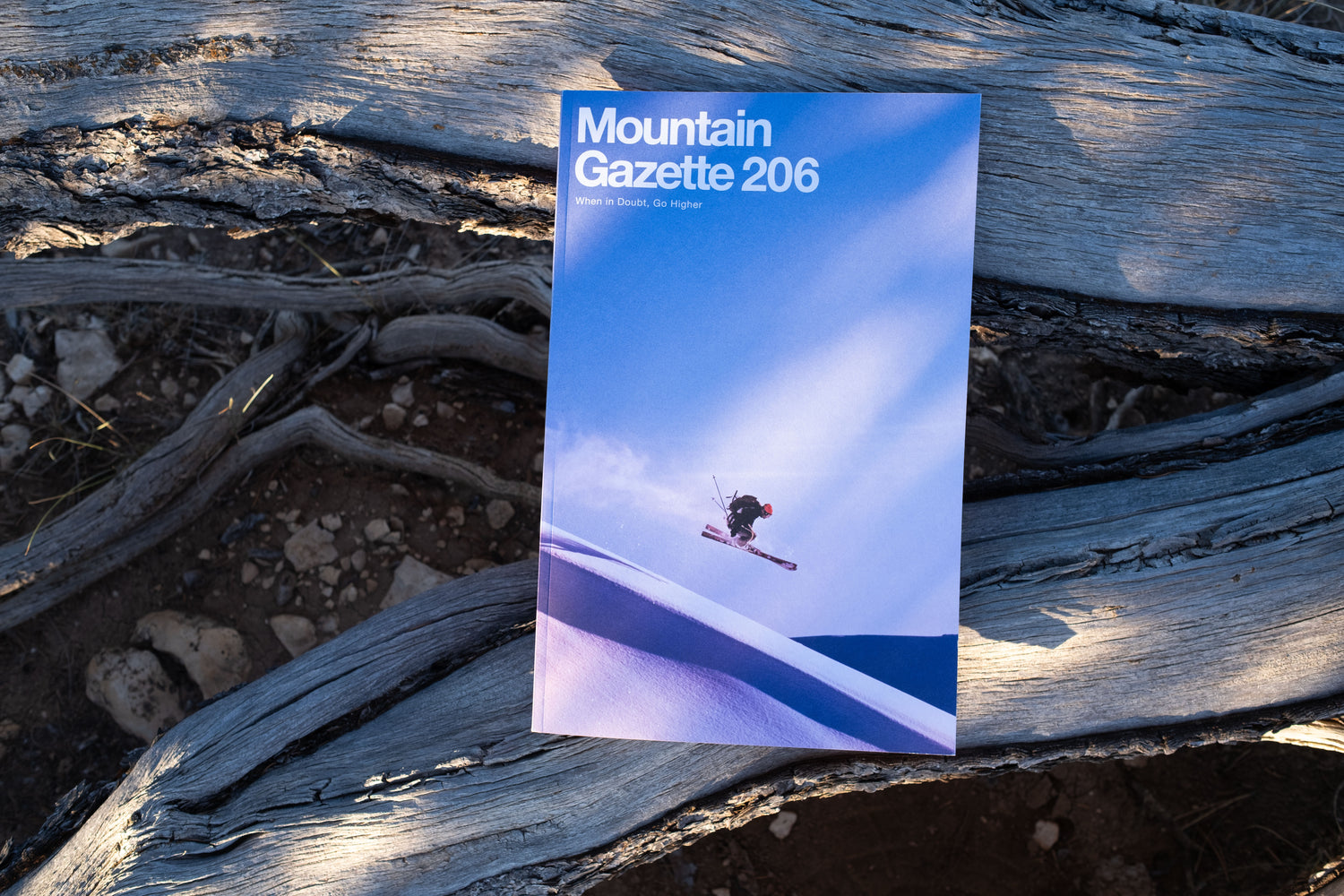 A printed magazine or gazette titled "Mountain Gazette 206" laying on weathered wood outdoors. The cover shows skier Jeremy Nobis in the air against a blue sky.