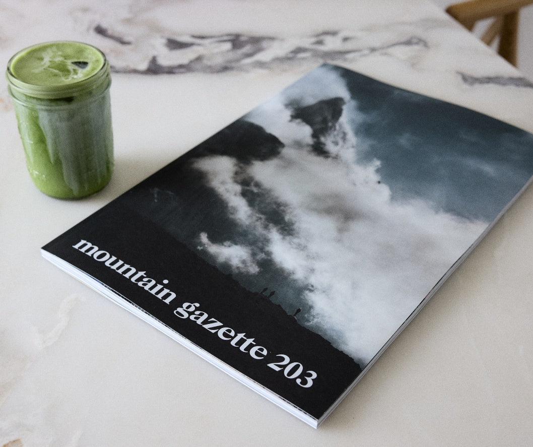 Mountain Gazette 203 the spring issue of Mountain Gazette magazine on a marble counter next to a drink