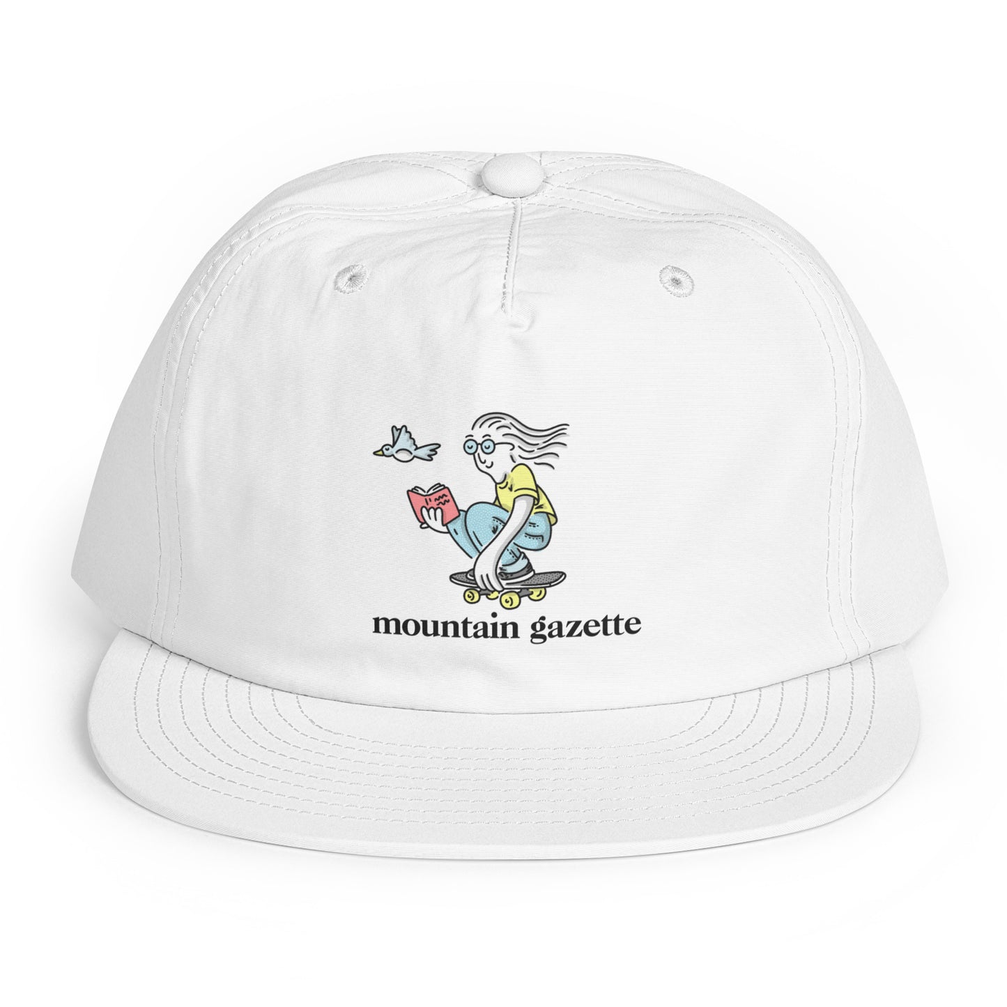 White cap with a graphic design of a skateboarder reading a book and 'mountain gazette' text on a white background